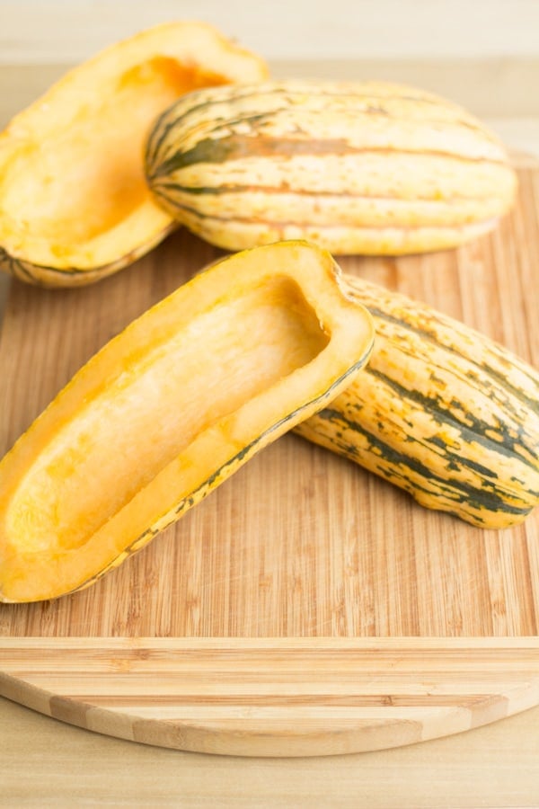 Halved Delicata Squashes on a chopping board 