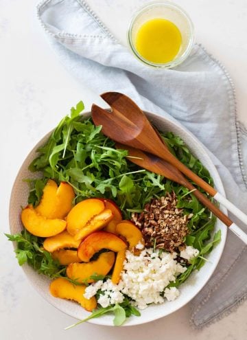 sliced nectarine, crumbled feta, chopped pecan on arugula in salad bowl