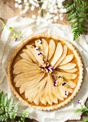Top view of Simple Pear Tart on a white napkin and some flowers.