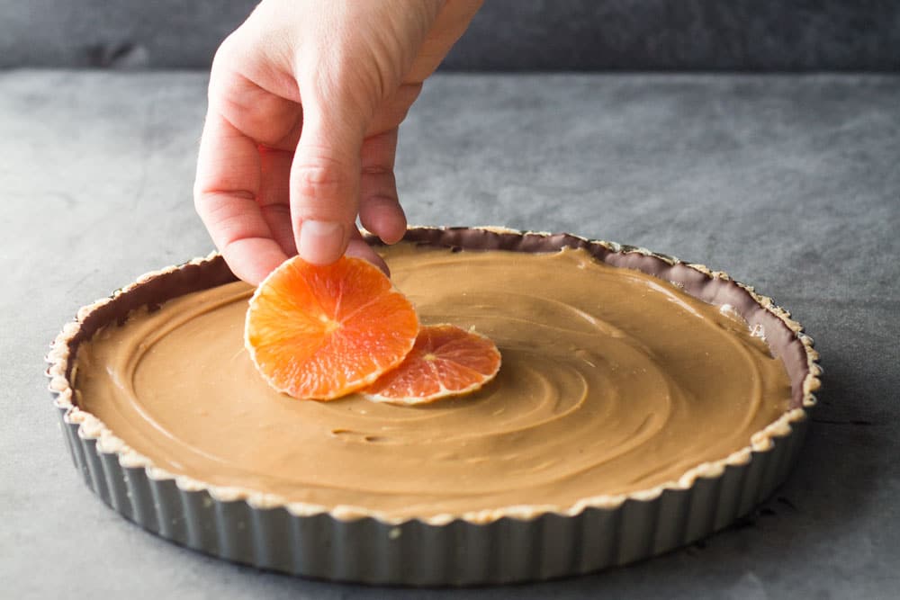 placing oranges into a chocolate orange tart