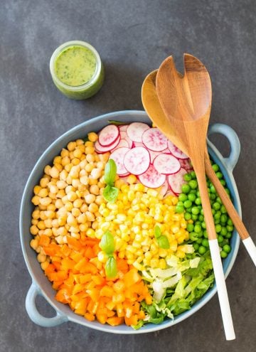 Top view of Romaine Lettuce Salad with a jar of Herb Vinaigrette, and a wooden salad fork and spoon.
