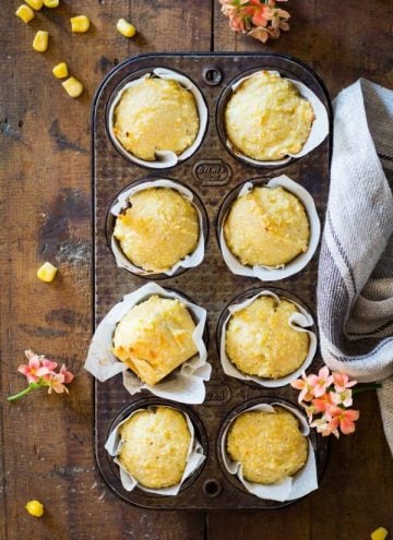 Cornbread muffins in parchment paper in a muffin tin.