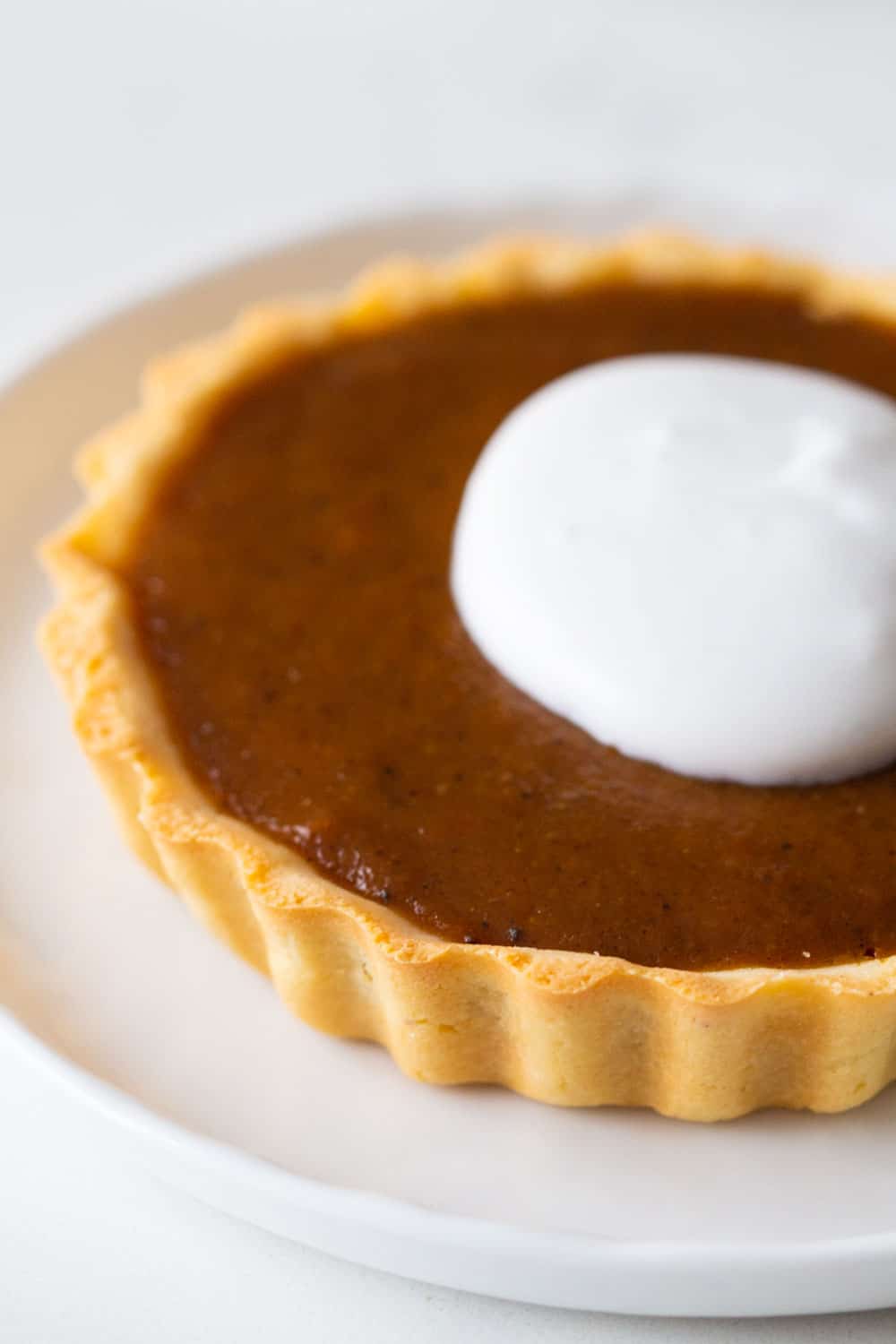 Close up of pumpkin pie with whipped cream on top.