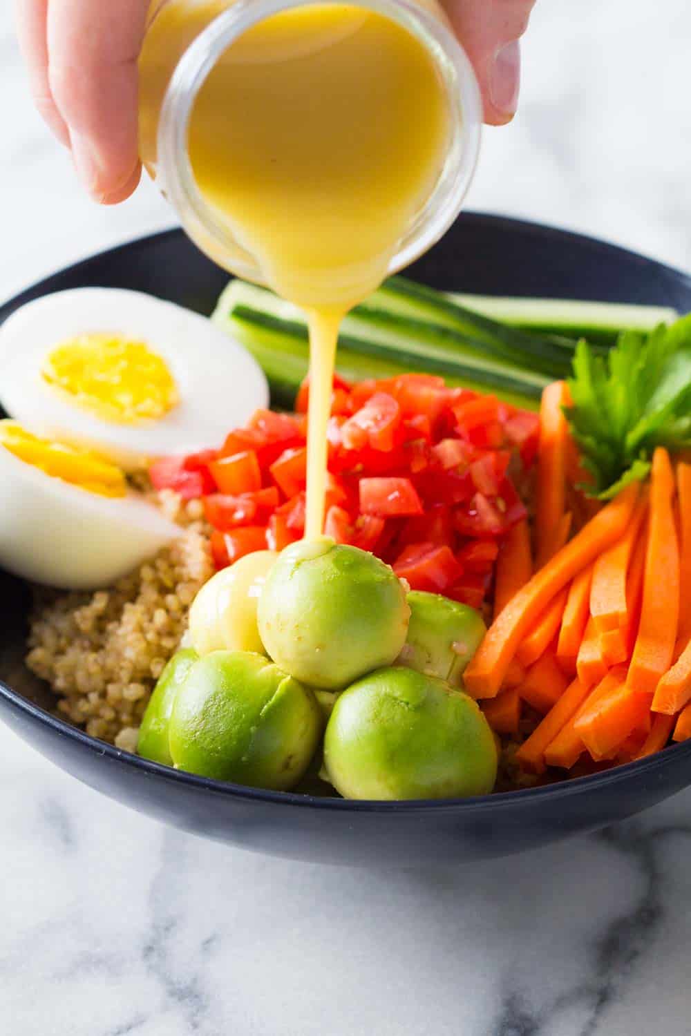 Lemon Tahini Dressing poured over avocado on a instant pot quinoa bowl.