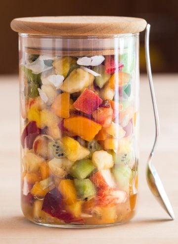 Mango Fruit Salad in a jar with a spoon leaning against it.
