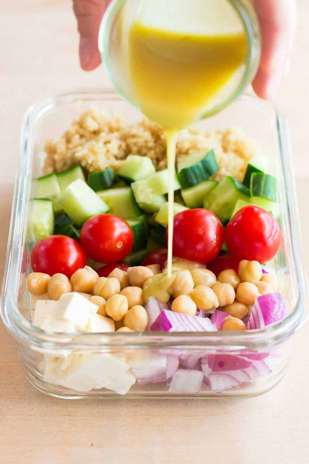 pouring lemon tahini dressing over healthy meal prep bowl