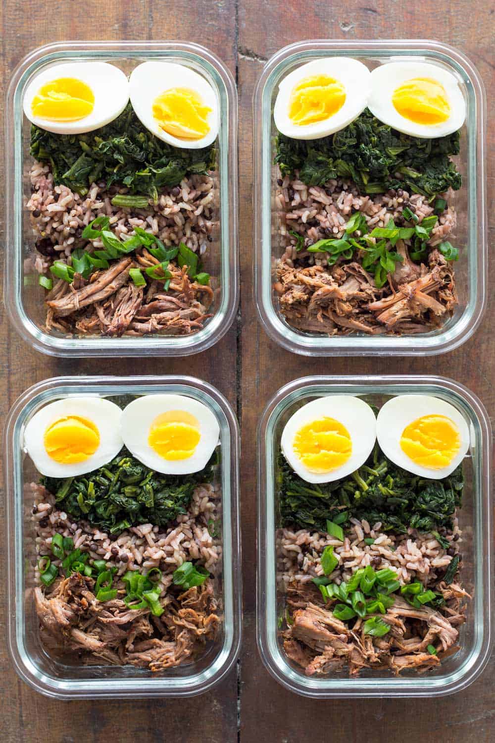 4 meal prep containers with crock pot roast, hard-boiled eggs, sautéed spinach, brown rice and puy lentils.