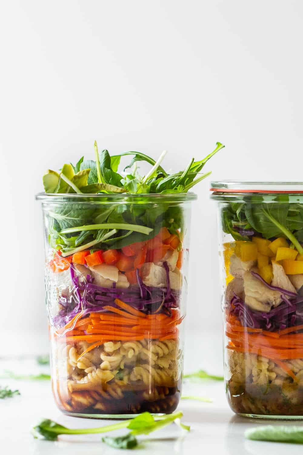 Pasta Salad with Chicken in two jars filled in layers. One dark dressing, one light dressing.