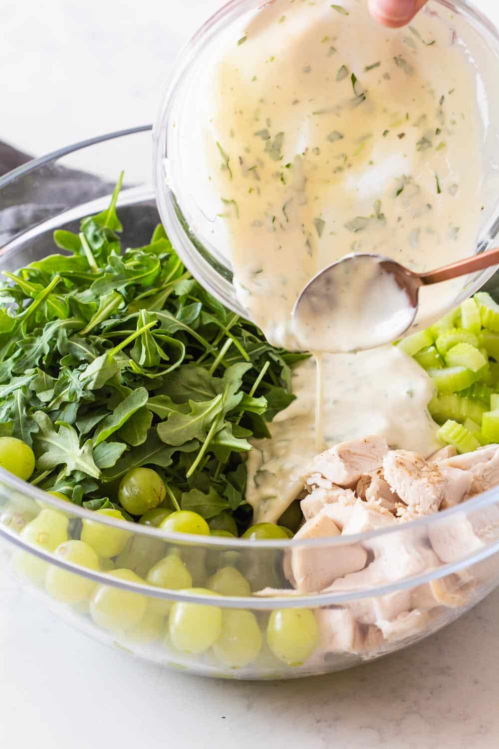 Yogurt Dressing being poured over Chicken Salad Recipe with Grapes