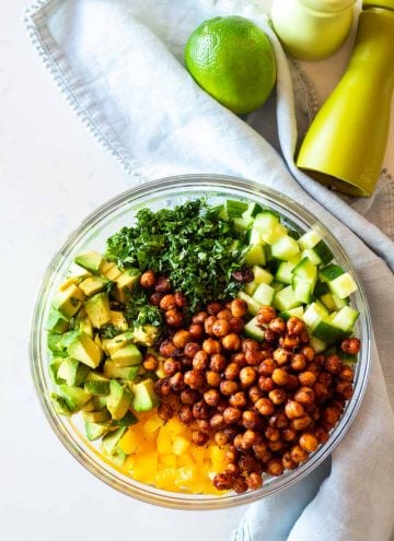 Cucumber Avocado Salad with crispy spicy chickpeas in a glass bowl next to a pale blue napkin