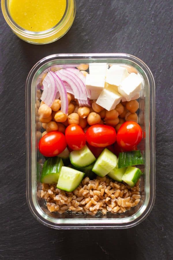 vegetarian meal prep bowl containing farro, cucumber, grape tomatoes, chickpeas, farro, red onion, and lemon tahini dressing