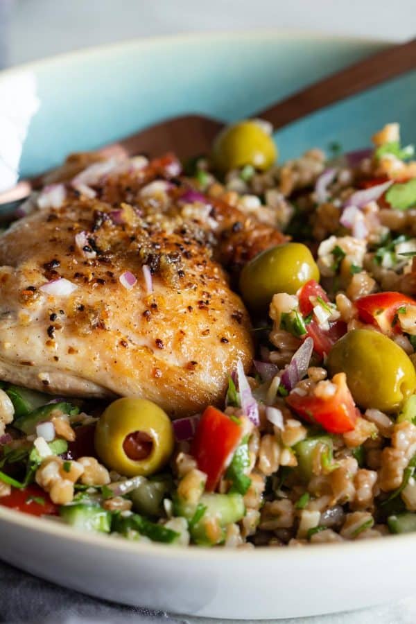 Mediterranean farro salad topped with a pan-seared chicken thigh
