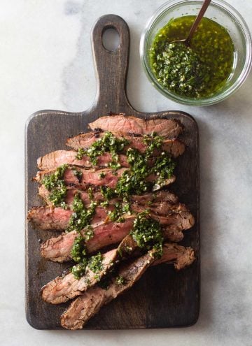 Flank Steak on a cutting board and Chimichurri in a jar
