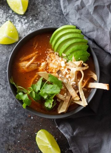 Instant Pot Chicken Tortilla Soup in a black bowl topped with avocado tortilla strips and cilantro