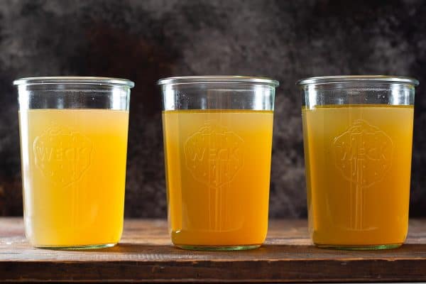 Three glass jars filled with golden chicken bone broth