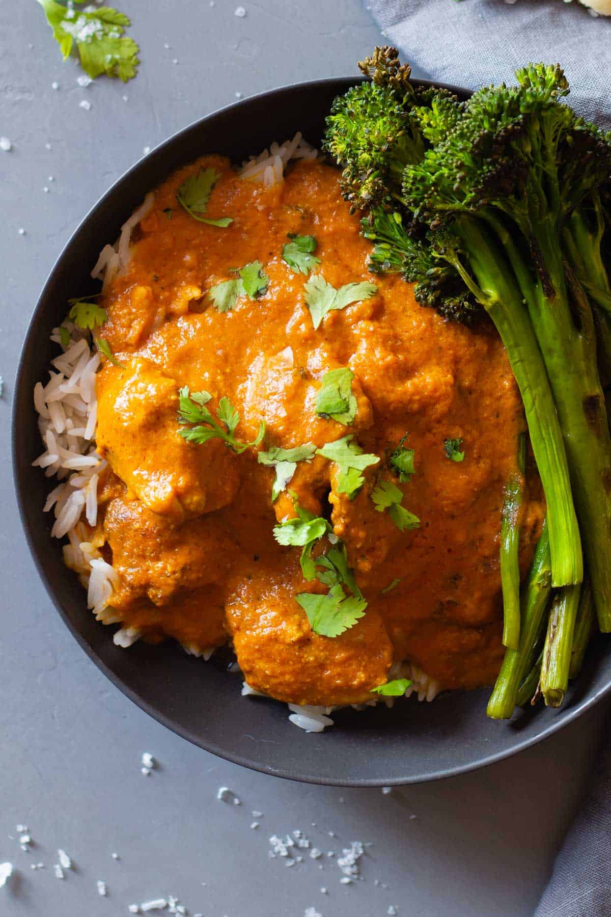 texture of butter chicken in a grey bowl over white rice