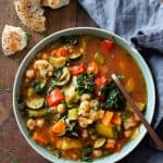 Vegetable Soup made in the instant pot in a blue bowl on a wooden table and bread and a napkin next to the bowl