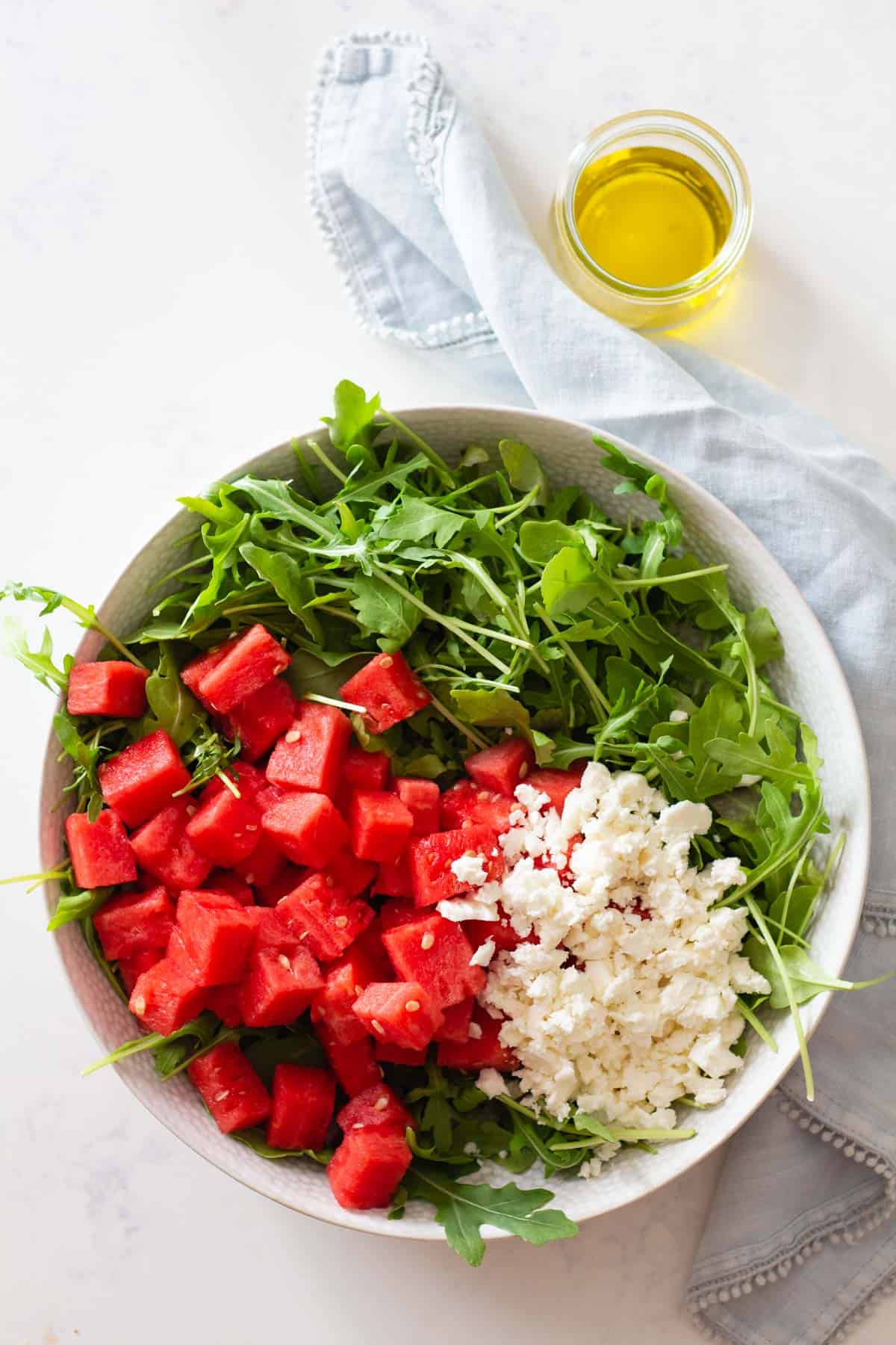 Watermelon and crumbled feta on top of arugula in a salad bowl