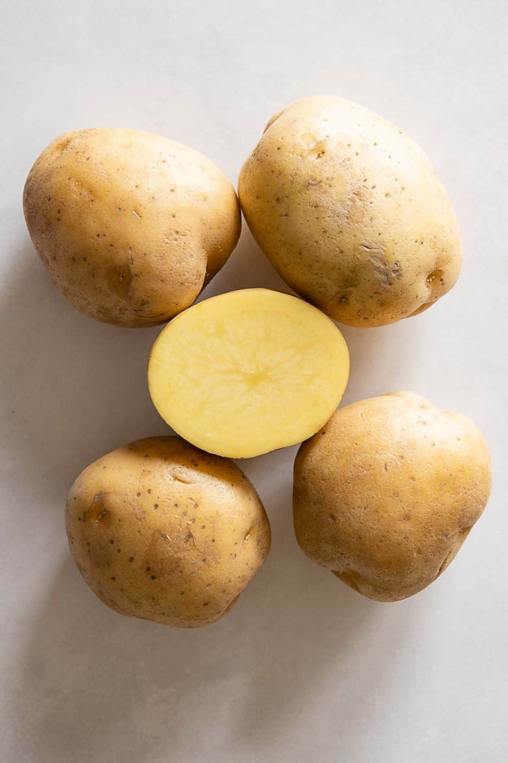 5 Yellow-fleshed potatoes, one cut open to show color. Instant Pot Mashed Potatoes recipe
