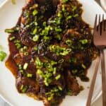 Lemongrass ginger chicken thighs on a white plate.