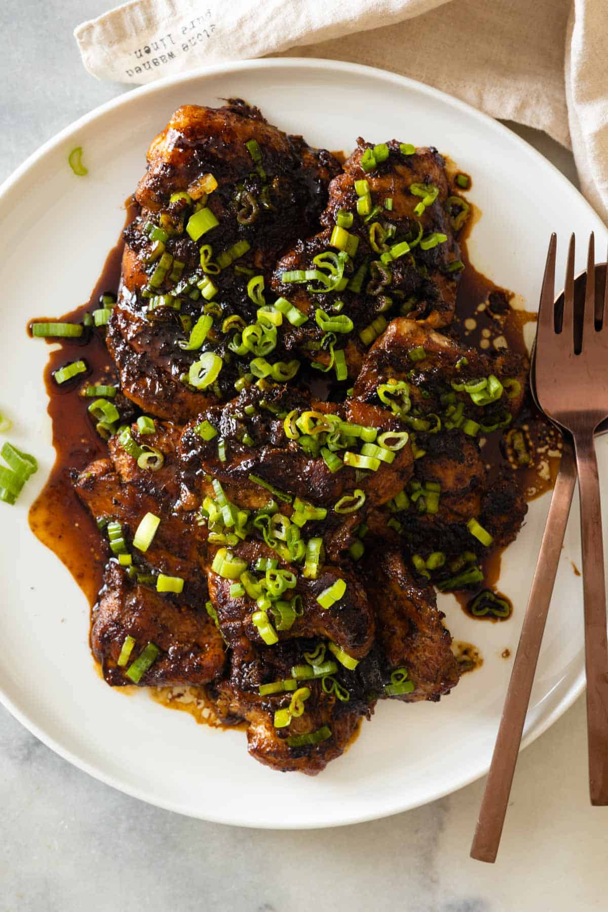 Lemongrass ginger chicken thighs on a white plate.