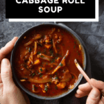 Cabbage Roll Soup in a bowl with hands holding bowl and spoon with text overlay for Pinterest.
