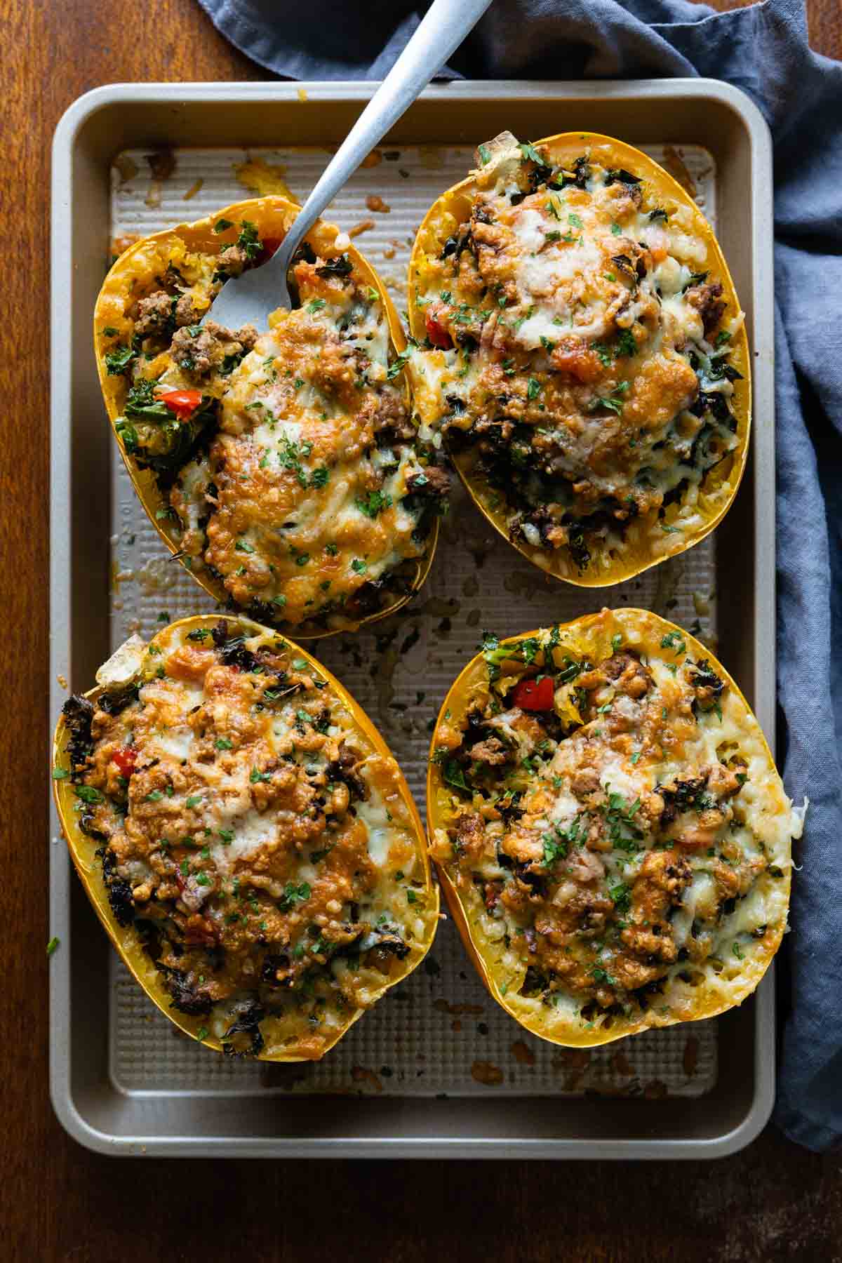 4 meat stuffed spaghetti squash halves on a baking sheet.