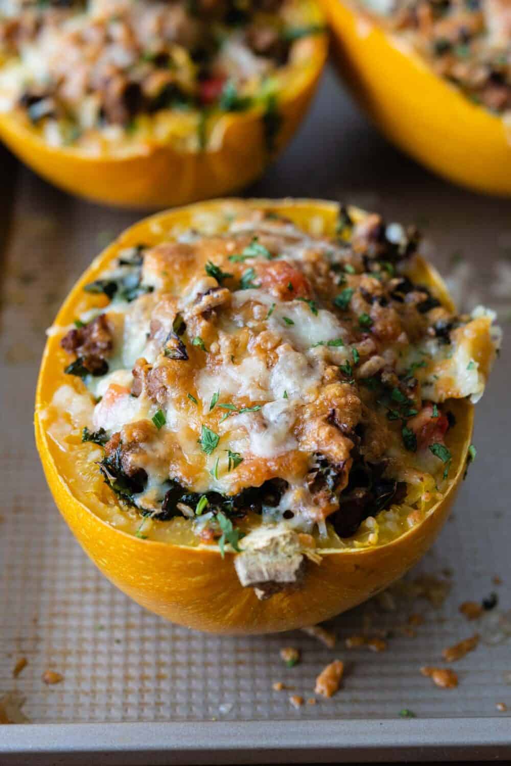 melted cheese covered, meat stuffed spaghetti squash half on a baking sheet.