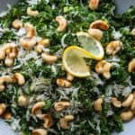 White rice, kale, and cashews in a bowl topped with a slice of lemon.