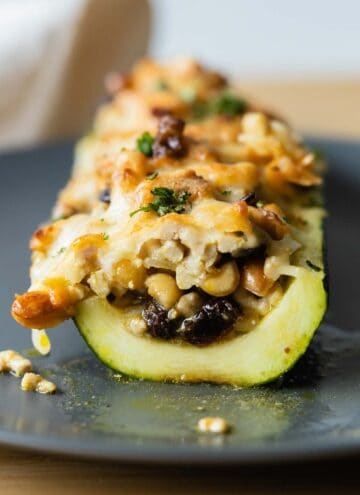 Cut-up stuffed zucchini boat on a gray plate.
