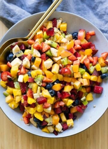 Fruit Salad mixed up and in a large grey bowl.