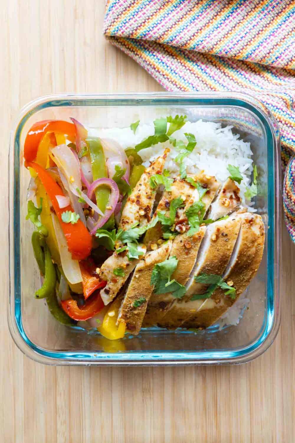 Glass meal prep container with chicken, rice, and bell peppers.