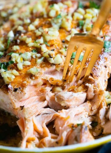 Closeup showing texture of cooked pan-seared salmon with garlic on top.