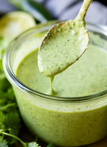 Aji Verde Sauce in a glass bowl with a golden spoon being dipped into it.