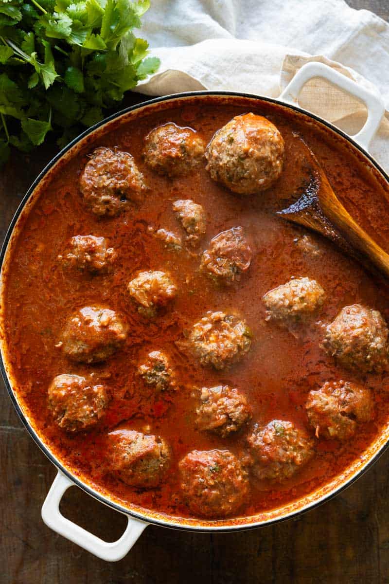 Albondigas in tomato sauce in a large white pan.